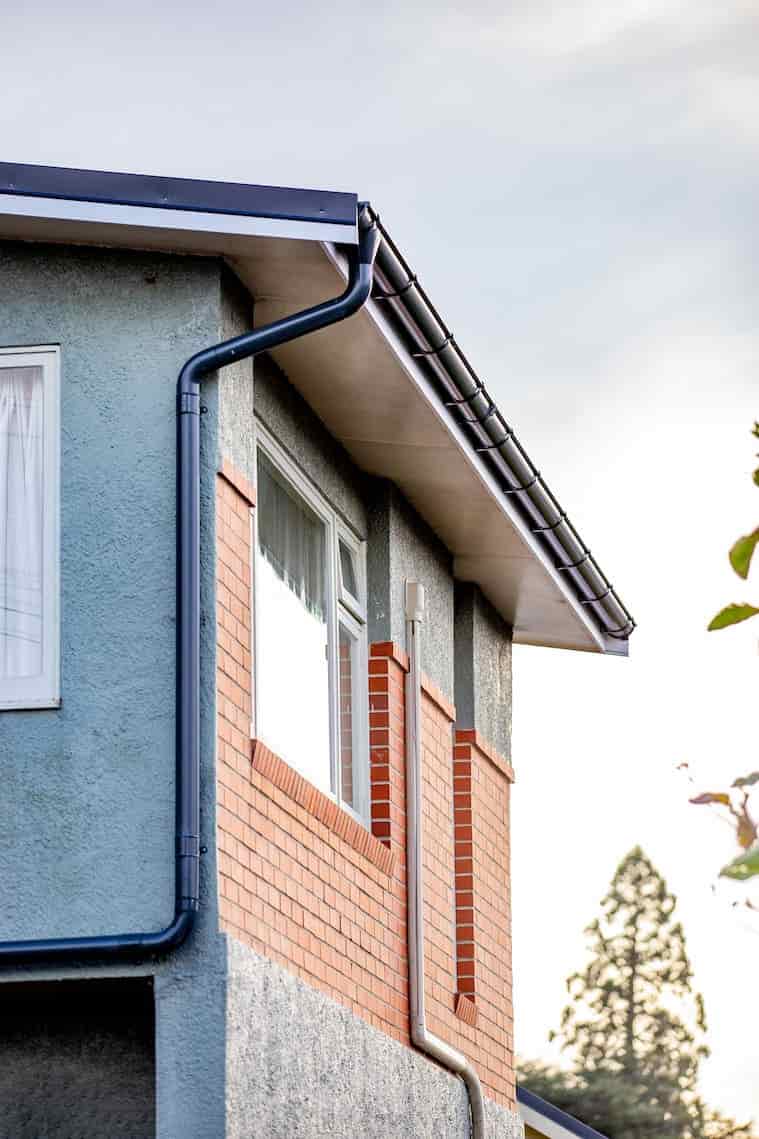 A house with a gutter attached to its side, directing rainwater away from the roof.