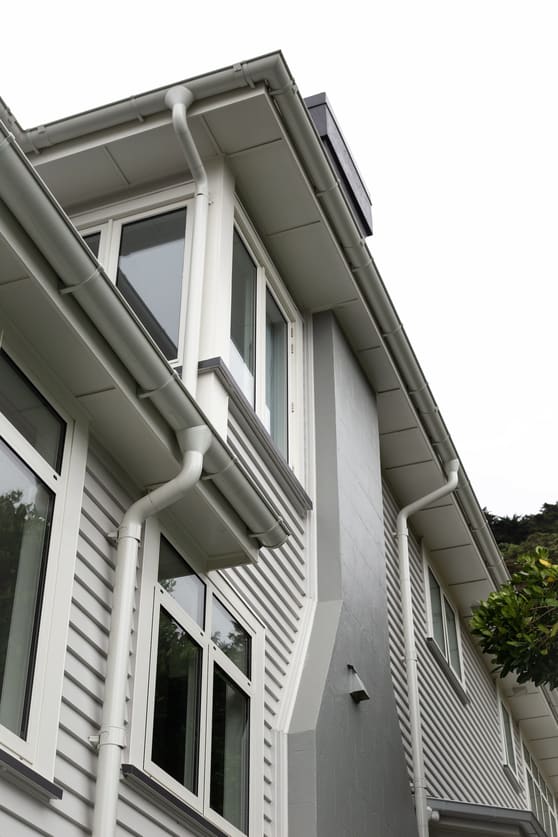 A house with a white gutters and downpipes, standing tall and inviting.